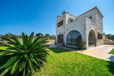 an exterior view of a stone house with a palm tree at FOS residence - ΦΩΣ ,luxury villa in Chania Town