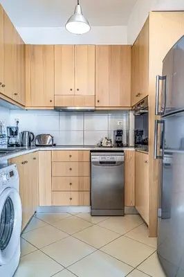 a kitchen with wooden cabinets and a washer and dryer at DIMITRA apartment with private pool and sea view -the ground floor of a two storey building in Daratso