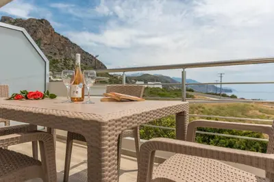 a table with wine glasses and flowers on a balcony at Allview apartments in Palaiochóra