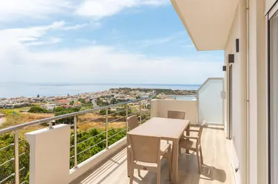 a balcony with a table and chairs and a view of the ocean at Allview apartments in Palaiochóra