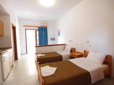 a hotel room with two beds and a kitchen at Irini Apartments in Plataniás