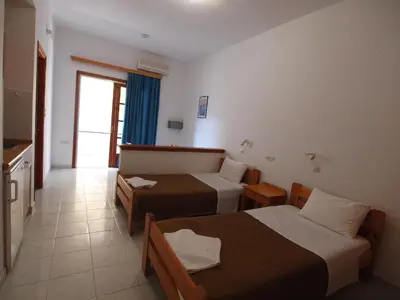 a hotel room with two beds and a kitchen at Irini Apartments in Plataniás