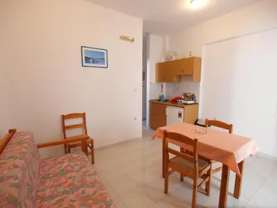 a living room with a table and chairs and a kitchen at Irini Apartments in Plataniás