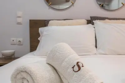 a white towel on a bed with white pillows at Mariviky design apartment in Chania Town