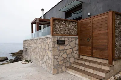 a house with a wooden door and a stone wall at Villa Yasemi panoramic sea view in Chania Town