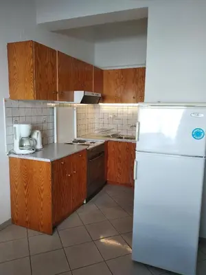 a kitchen with wooden cabinets and a white refrigerator at Ton Mari Apartments in Palaiochóra