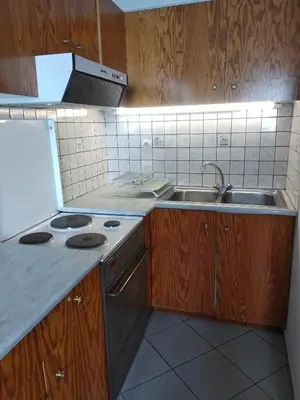 a kitchen with wooden cabinets and a sink and a stove at Ton Mari Apartments in Palaiochóra