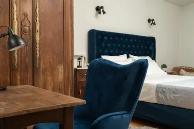 a bedroom with a bed with a blue chair and a table at Mansion D in Galatás