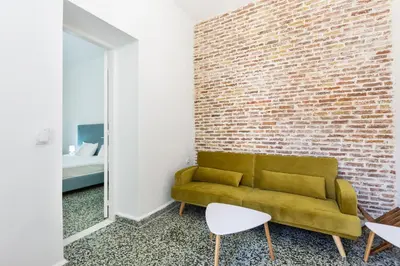 a living room with a couch and a brick wall at MV Living - Residence in Chania Town