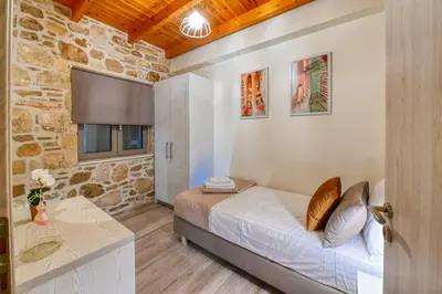 a bedroom with a bed in a room with a stone wall at Petros Luxury Traditional House - Villa in Kissamos