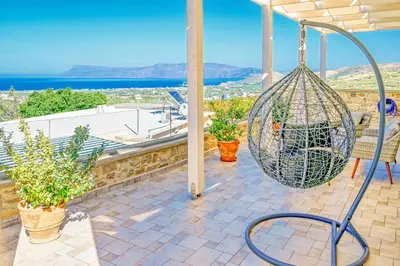 a swing on a porch with a view of the ocean at Petros Luxury Traditional House - Villa in Kissamos
