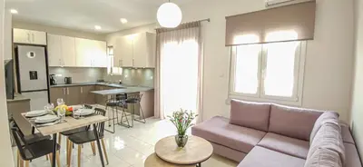 a living room and kitchen with a couch and a table at Fully renovated apartment in the city centre with roof garden! 3 minutes from the bus station and 6 minutes from the old town in Chania Town