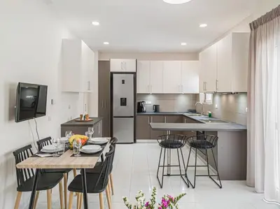 a kitchen with a table and chairs and a kitchen with white cabinets at Fully renovated apartment in the city centre with roof garden! 3 minutes from the bus station and 6 minutes from the old town in Chania Town