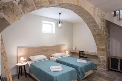 a bedroom with two beds and a stone wall at Dinas's Cottage Ideal Base for Balos and Elafonisi in Kaloudhianá
