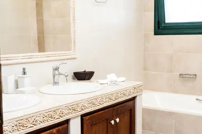 a bathroom with two sinks and a tub and a mirror at Villa Vallia - Villa Marina in Kato Galatas