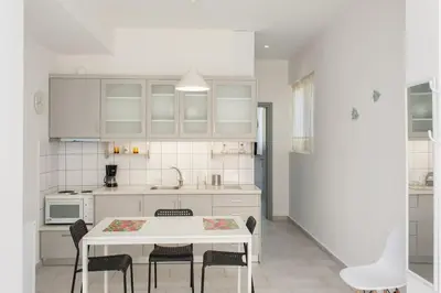 a white kitchen with a white table and chairs at Glaros Studios in Kalamaki Chanion