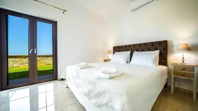 a bedroom with a white bed with a large window at Grand Olympia,Luxury, spacious indoor&outdoor area in Kissamos
