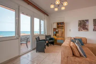 a living room with a couch and a view of the ocean at Agiazi Beachfront Apartment in Chania Town