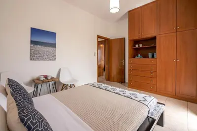 a bedroom with a bed and a wooden cabinet at Agiazi Beachfront Apartment in Chania Town