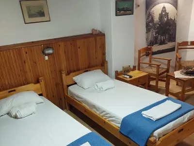 a bedroom with two beds and a table and chairs at Guesthouse Chryssoula in Chania Town