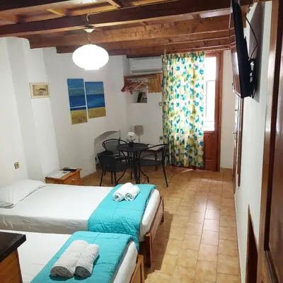 a bedroom with two beds and a dining room with a table at Guesthouse Chryssoula in Chania Town