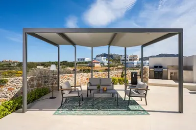 a pavilion with chairs and a table on a patio at Villa Afeidia in Tersanas