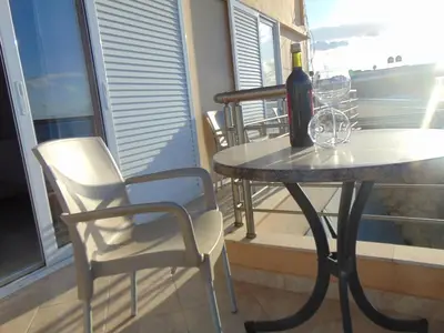 a table with a bottle of wine and chairs on a balcony at Comfy Beachfront Litinas Casa with SeaView in Chania Town