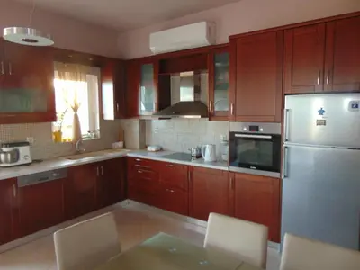 a kitchen with wooden cabinets and a stainless steel refrigerator at Comfy Beachfront Litinas Casa with SeaView in Chania Town