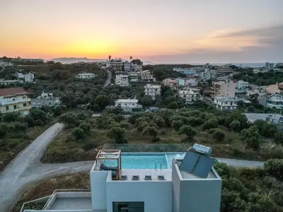 a villa with a swimming pool and a sunset at Soleado Villa Chania rooftop heated pool in Chania Town