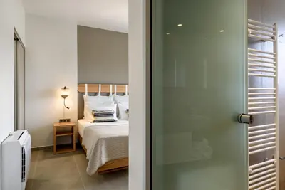 a bedroom with a bed with white sheets and a window at Soleado Villa Chania rooftop heated pool in Chania Town