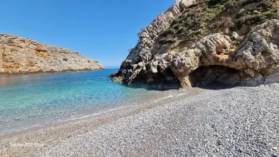 a rocky beach with blue water and a rocky cliff at ERIS House in Kissamos