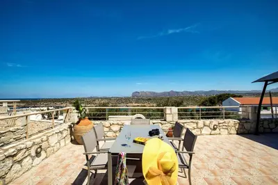 a table and chairs on a patio with a view at Vagioni Seaside Villa in Kounoupidhianá