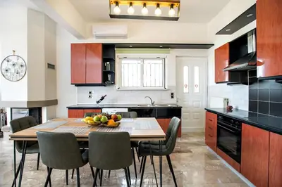 a kitchen with a wooden table with chairs and a dining room at Vagioni Seaside Villa in Kounoupidhianá