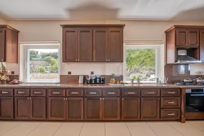 a large kitchen with wooden cabinets and two windows at Michael's Villa in Kissamos