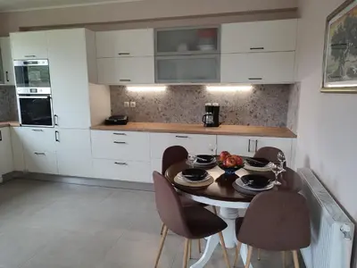 a kitchen with white cabinets and a table and chairs at Villa Lakki's Ori in Lákkoi