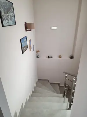 a staircase with white walls and a table and a stair case at Villa Lakki's Ori in Lákkoi