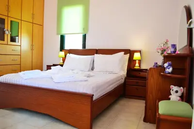 a bedroom with a bed with white sheets and a teddy bear at Belle Verte Villa Maleme in Maleme