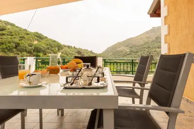 a table with food and drinks on a balcony at Villa Araxovoli in Palaiochóra