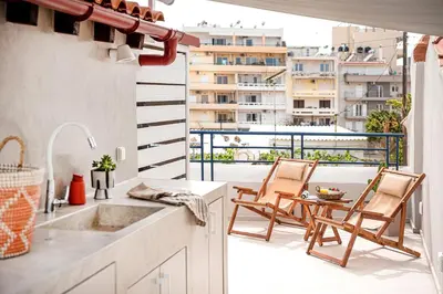 a kitchen with a sink and two chairs on a balcony at New Boutique Venetian apartments - La Casa Nove in Chania Town
