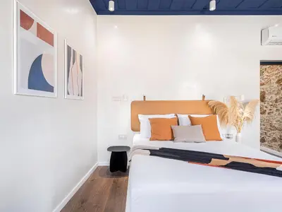 a white bedroom with a bed with orange pillows at New Boutique Venetian apartments - La Casa Nove in Chania Town
