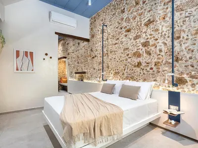 a bedroom with a large white bed with a stone wall at New Boutique Venetian apartments - La Casa Nove in Chania Town
