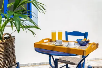 a table with a blue chair and a blue table with a breakfast at Beach House Kalamaki steps away from the beach in Galatás