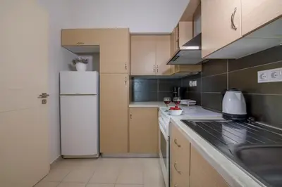 a kitchen with a white refrigerator and a sink at Erontas Apartment in Palaiochóra