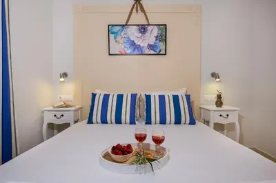 a bed with two glasses of wine and a bowl of fruit at Erontas Apartment in Palaiochóra