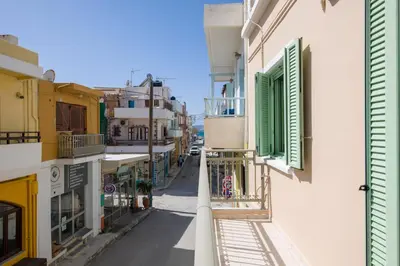 an alley with green shutters on a building at Erontas Apartment in Palaiochóra