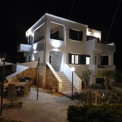 a white house at night with a table and stairs at Paradisos Villa - Chania, Crete in Litsárdha