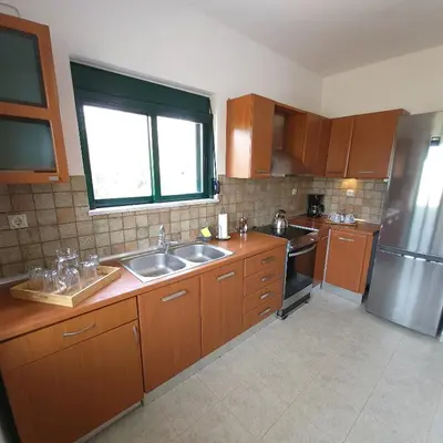 a kitchen with wooden cabinets and a stainless steel refrigerator at Paradisos Villa - Chania, Crete in Litsárdha