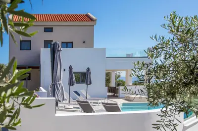a pool with chairs and umbrellas next to a building at Casa Galatas in Galatás