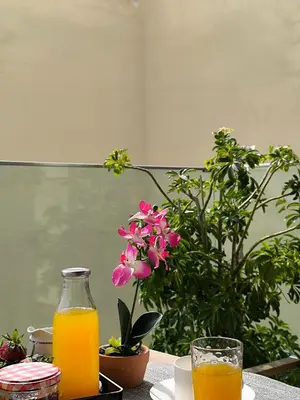 a table with a glass of orange juice and a flower at Avanti Chania Luxury Apartment in Chania Town