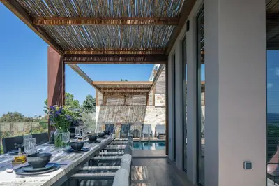 an outdoor dining area with a table and chairs and a pool at Omma Villas in Chania Town